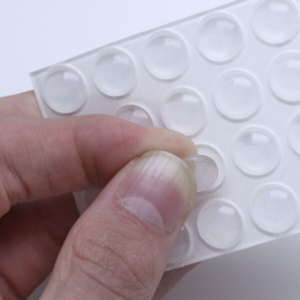 Persons fingers peeling off Slipstick CB440 10mm Round Clear Rubber Bumpers from a sheet of them